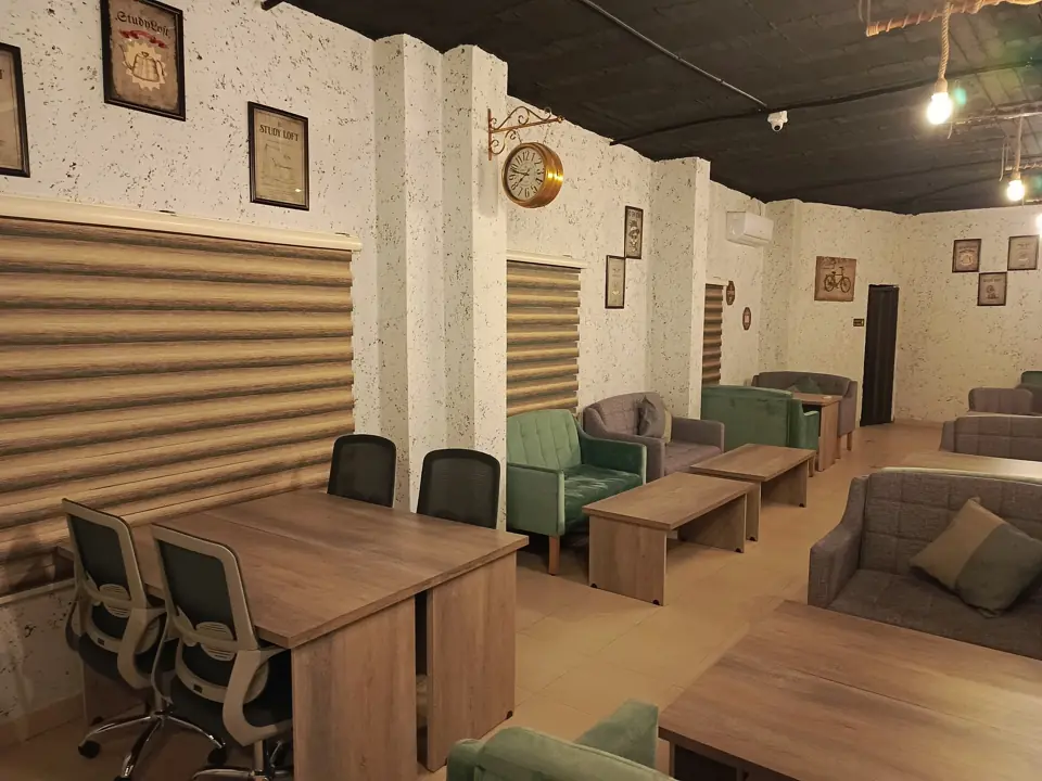 Individual study desks and comfortable lounge seating beneath vintage wall art at Study Loft